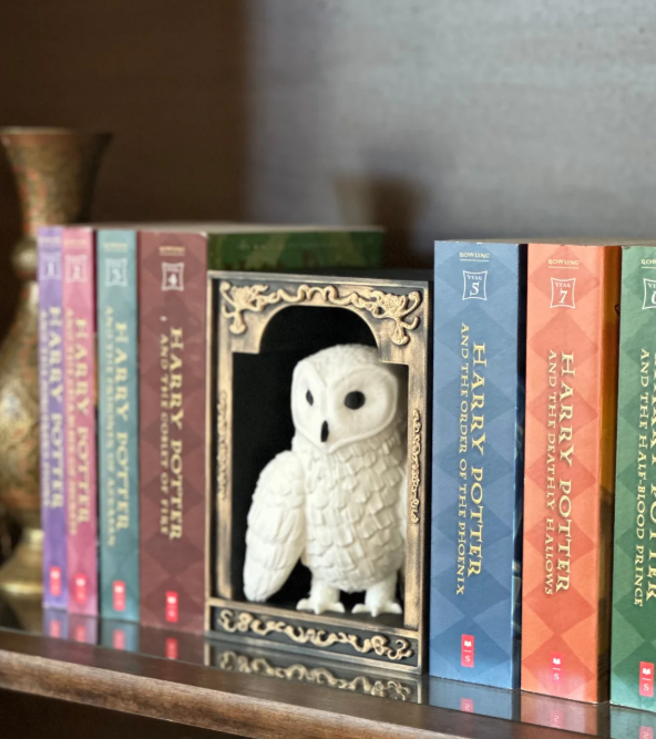 Decorative owl figure in front of Harry Potter bookshelf arrangement