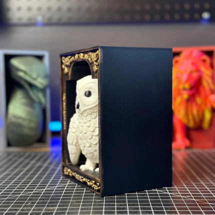 White figurine in a dark blue box with gold accents on a grid surface.