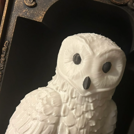 White owl figurine with black eyes against a dark background